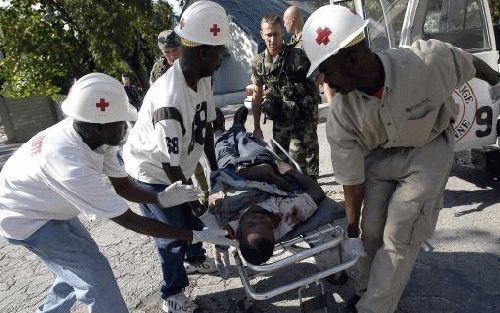 PORT-AU-PRINCE - Hulpverleners dragen in HaÃ¯ti een gewonde weg. Bij protesten kwamen zes mensen om het leven. Foto EPA