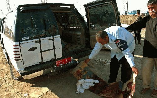 Een Irakeese politieman inspecteert de auto van een Nederlandse en een Duitse ingenieur, die dinsdag zijn overleden na een schietpartij. Zij waren op weg van Baghdad naar Karbala. Foto EPA