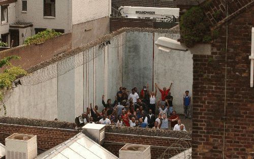 ROERMOND â€“ Gedetineerden staan op de luchtplaats van het huis van bewaring in Roermond. De gevangenen weigerden maandagavond terug te gaan naar hun cel nadat er ’s middags een korte maar hevige brand had gewoed in het detentiecentrum. Foto ANP