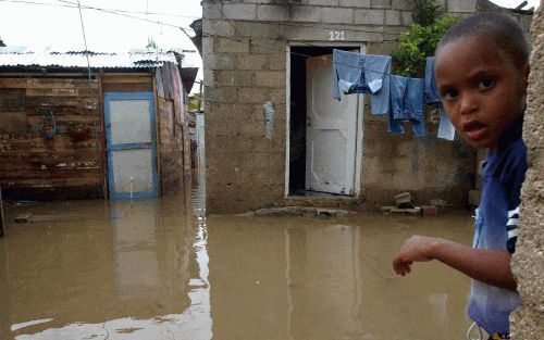 SANTO DOMINGO - Een Dominicaans jongetje kijkt naar een ondergelopen straat bij zijn huis in de hoofdstad Santo Domingo. Overstromingen als gevolg van noodweer hebben in de Dominicaanse Republiek en HaÃ¯ti aan zeker 363 inwoners het leven gekost. Honderde