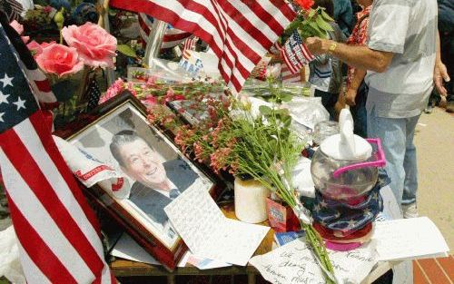 MOORPARK â€“ Terwijl bezoekers in Moorpark wachten op vervoer naar de Ronald Reagan Bibliotheek in Simi Valley, CaliforniÃ«, bekijken ze de vele aandenkens die zijn neergelegd ter herinnering aan de zaterdag overleden oud president Ronald Reagan. Foto EPA