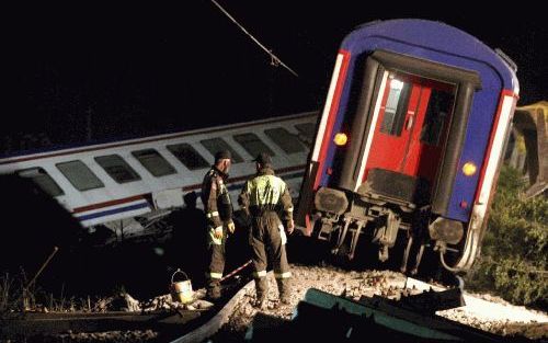 Twee reddingsmedewerkers bij het treinongeluk dat donderdag 36 doden heeft veroorzaakt. Zeker 68 personen raakten gewond. Foto EPA