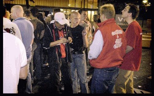 Twee medewerkers van de stichting Naar House in gesprek met bezoekers van het muziekfestival Resurreqtion.