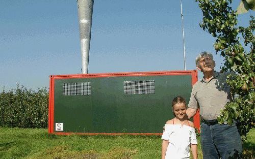 KRABBENDIJKE - Fruitteler Theo Vogelaar, op de foto samen met zijn kleindochter, schakelt bij een naderende hagelbui zijn kanon in. Of de methode werkt, is de vraag. Voor zeven Zeeuwse telers is 2004 een proefjaar. - Foto VisionPhoto