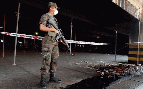 Een Paraguyanse soldaat voor de parkeerplaats van de supermarkt die verwoest is door de brand. De brand heeft meer dan 400 levens geeist. Foto EPA