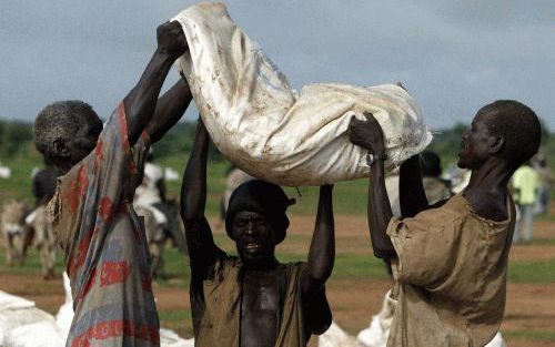 DARFUR â€“ Ontheemden in de Sudanese provincie Darfur dragen een zak met eten naar hun onderkomen. Het eten werd gedropt door een vliegtuig van het Wereldvoedselprogramma (WFP) van de Verenigde Naties. - Foto EPA