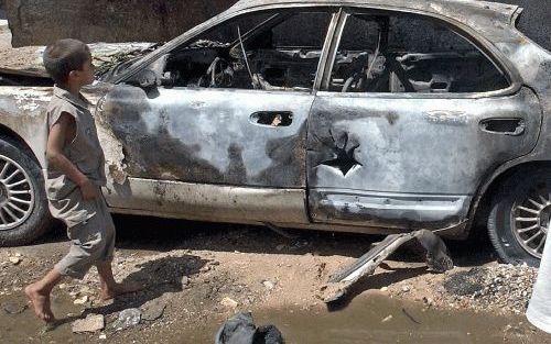 BAGDAD â€“ Een jongetje passeert een verwoeste auto in de Iraakse hoofdstad Bagdad. Amerikaanse troepen en sjiitische opstandelingen leverden donderdag en vrijdag opnieuw slag in de uitgestrekte buitenwijk Sadr City. Foto EPA