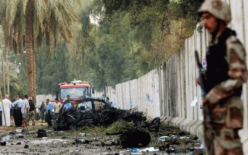 BAGDAD â€“ Een lid van de nationale garde bewaakt in de Iraakse hoofdstad Bagdad de plaats waar een aanslag met een autobom is gepleegd. Vier mensen vonden dinsdagochtend de dood bij de aanslag, die een aantal ministers als doelwit had. Foto EPA