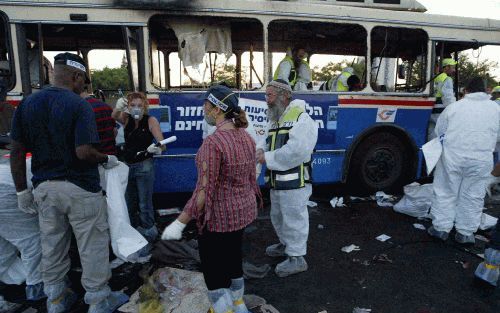 BEERSHEVA â€“ IsraÃ«liÃ«rs verzamelen zich rond een verwoeste bus in Beersheva. Dinsdag kwamen, na een periode van relatieve rust, bij een dubbele Palestijnse zelfmoordaanslag op twee bussen in de IsraÃ«lische woestijnstad achttien mensen om het leven. Fo