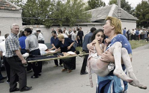 BESLAN â€“ Een vrouw draagt een meisje in haar armen dat uit het schoolgebouw in Beslan, Noord OssetiÃ«, wist te ontsnappen. Foto EPA