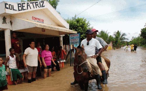 ARENOSA â€“ Twee dorpelingen uit de Dominicaanse Republiek waadden zaterdag op een paard door het water nadat de orkaan Jeanne had toegeslagen. Grote delen van de Dominicaanse Republiek kwamen het afgelopen weekeinde blank te staan. Foto EPA