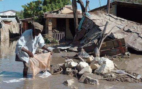 GONAIVES - Een inwoner wast zijn kleren in de overstroomde straten van de stad Gonaives. Het dodental is inmiddels opgelopen tot 1147. Foto ANP