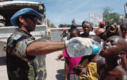 GONAIVES â€“ Een VN soldaat geeft een HaÃ¯tiaanse jongen te drinken in de door de orkaan Jeanne getroffen stad GonaÃ¯ves. Duizenden slachtoffers van het natuurgeweld zitten nog zonder voedsel en drinkwater. Foto EPA