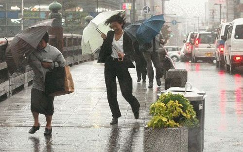 KYOTO â€“ Inwoners van de Japanse stad Kyoto vochten gisteren tegen stormwind en regenval als gevolg van de tyfoon Tokage, die het zuidelijk deel van Japan teisterde. Het dodental als gevolg van het natuurgeweld is inmiddels opgelopen tot 55. Foto EPA