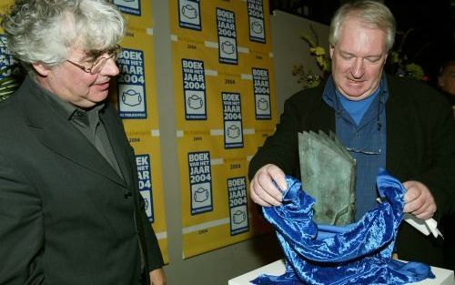 AMSTERDAM â€“ Schrijver Geert Mak (l.) kijkt toe hoe Emile Brugman van uitgeverij Atlas de NS Publieksprijs onthult. De prijs die Mak gisteren won, levert zijn ”In Europa” het predikaat Boek van het Jaar 2004 op. Foto ANP