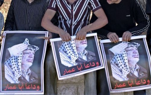 RAMMALAH - Palestijnen zitten in de schaduw bij het hoofdkwartier van de overleden Palestijnse president Arafat. Arafat zal daar rond 15.00 uur Nederlandse tijd begraven worden. Foto EPA