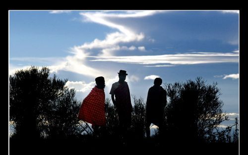 Drie Karamajong-mannen staan roerloos in het licht van de ondergaande zon in Karamojoland. Het gebied wordt al jarenlang door geweld geteisterd, waardoor de ontwikkeling nauwelijks van de grond komt. Foto RD, Sjaak Verboom