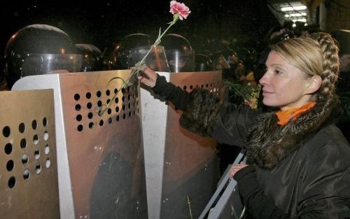 Julia Timoshenko â€“een van de belangrijkste bondgenoten van de oppositionele presidentskandidaat Viktor Joesjtsjenkoâ€“ plaatst een anjer in een wapenschild van de OekraÃ¯ense oproerpolitie, die het presidentiÃ«le paleis in Kiev bewaakt. In Kiev betoogde