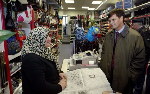 ROTTERDAM - Premier Balkenende woensdag in gesprek met een verkoopster in een schoenenwinkel, tijdens een kort bezoek aan de Rotterdamse winkelstraten Groene Hilledijk en Beijerlandselaan. Balkenende sloot zich aan bij een werkbezoek van burgemeester Opst