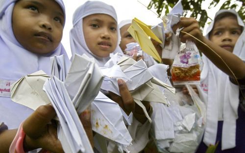 PATTANI â€“ Thaise kinderen tonen kunstig gevouwen vogels van papier. Vliegtuigen hebben gisteren boven het zuiden van Thailand ruim 120 miljoen papieren kraanvogels gedropt als teken van vrede in de richting van de moslims die daar wonen. Foto EPA