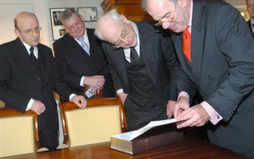 DEN HAAG â€“ De GBS bestuursleden ds. A. van Heteren en J. Roza kijken samen met oud GBS directeur L. M. P. Scholten en kamervoorzitter Weisglas naar de nieuwe uitgave van de complete Statenvertaling uit 1637. Foto Jos van Leeuwen