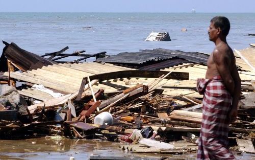 Een man bekijkt aan de kust van de Srilankaanse stad Lunawa de schade die de zeebeving heeft aangericht. Foto EPA