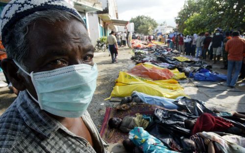 Een man uit het Indonesische Atjeh kijkt of er onder de slachtoffers familieleden van hem zijn. In IndonesiÃ« zijn drie dagen van nationale rouw afgekondigd. Foto EPA