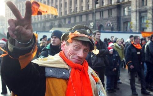 KIEV â€“ Een aanhanger van Viktor Joesjtsjenko maakt het V teken als de verkiezingscommissie bekendmaakt dat de pro westerse politicus de OekraÃ¯ense verkiezingen van afgelopen zondag heeft gewonnen. Foto EPA