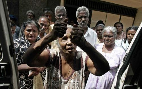 Terwijl omstanders meeluisteren, vertelt een oudere Srilankaanse vrouw hoe zij de vloedgolf in Galle heeft overleefd. Galle ligt ten zuiden van de hoofdstad Colombo. Foto EPA