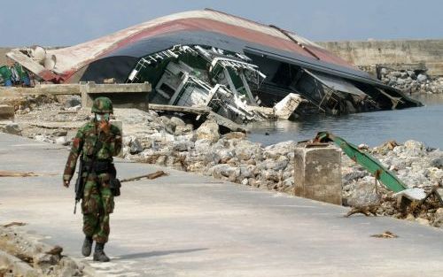 Deze Indonesische militair bedekt zijn gezicht als hij langs een verwoest schip loopt dat op het land is geslagen bij Lhoknga, ten zuidwesten van Banda Atjeh.