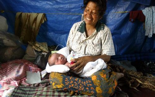 MEULABOH â€“ Een overlevende van de tsunami in Atjeh, de 35-jarige Nureini, glimlacht als ze haar twee dagen oude baby in handen houdt. Bijna een maand na de tsunami van 26 december â€“die haar dorp verwoestte en die ze als enige overleefde door in een bo