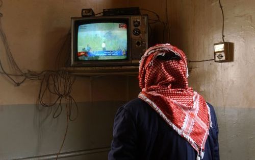 Een Irakees in de Jordaanse hoofdman Amman volgt in een theehuis via de Arabische nieuwszender al Jazeera het nieuws over Irak. Foto Yola Monakhov/Panos Pictures