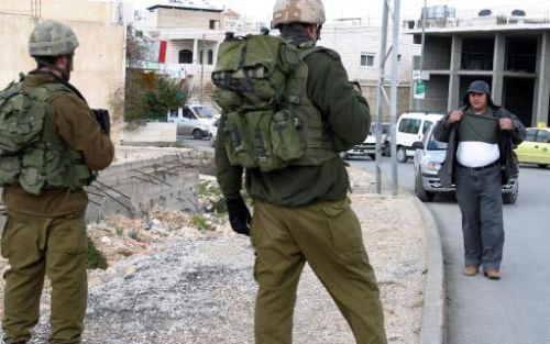 HEBRON - Israelische militairen controleren een Palestijn op het bezit van explosieven in Hebron. Foto EPA