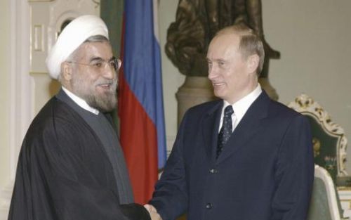 De Russische president Poetin schudt de hand van Rouhani, secretaris van het Hooggerechtshof in Iran, tijdens hun ontmoeting in Moskou vrijdag. Poetin zei dat Iran en Rusland op nucleair gebied blijven samenwerken.