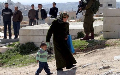 HEBRON â€“ Een IsraÃ«lische soldaat bewaakt een groepje Palestijnse mannen dat bij een controlepost in de buurt van Hebron is opgepakt. Foto EPA