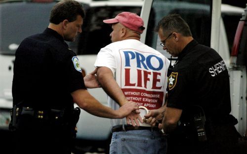 PINELLAS PARK - Een man wordt door de politie weggevoerd omdat hij Terri Shiavo een beker water wilde brengen. Foto EPA