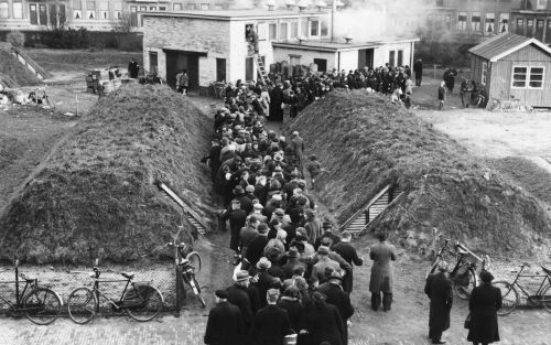 ROTTERDAM â€“ In de rij voor de gaarkeuken. Aan weerszijden schuilkelders. De foto maakt deel uit van de oorlogstentoonstellingen in het historisch museum van Rotterdam. - Foto Schielandshuis