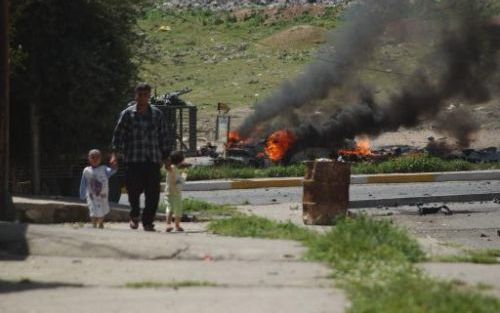 MOSUL - Een Iraakse man loopt met zijn kinderen langs een brandende auto. De auto is gebruikt bij een zelfmoordaanslag op een passerend konvooi van Amerikaanse legervoertuigen. Foto EPA