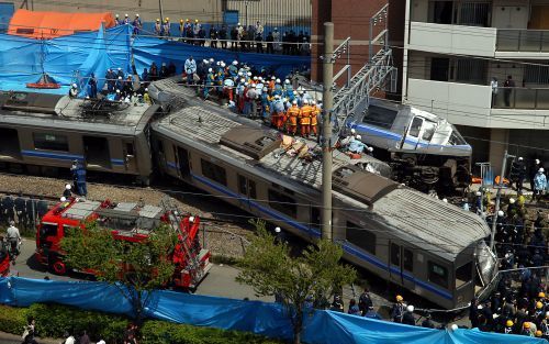 AMAGASAKI â€“ Japanse reddingswerkers proberen de passagiers te bereiken die nog vastzitten in de trein die maandag ontspoorde in Amagasaki, nabij Osaka. Het ongeluk gebeurde waarschijnlijk doordat de machinist te hard reed. Zeker vijftig mensen kwamen bi