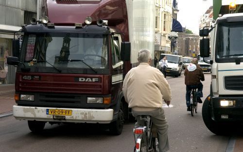 LEIDEN â€“ Fietsers kunnen maar nauwelijks tussen de vrachtwagens doorrijden. De overvolle Leidse Breestraat is erg krap. Foto Mark Lamers