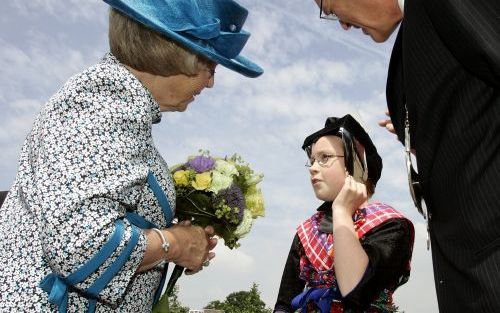 STAPHORST â€“ De 10 jarige Emilia Compagner heeft koningin Beatrix een bosje bloemen overhandigd na haar aankomst dinsdagmiddag in Staphorst per helikopter. Burgemeester J. D. Alssema kijkt lachend toe. Overijssel was de zesde provincie die de vorstin bez