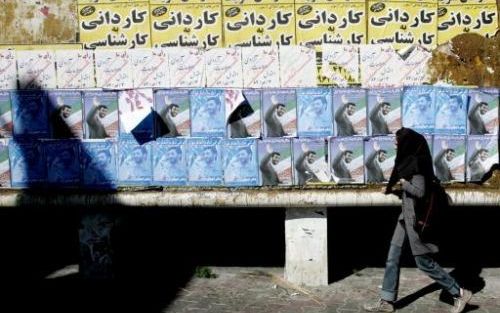 TEHERAN - Een Iraanse vrouw liep donderdag langs verkiezingsposters van presidentskandidaat Mahmood Ahmadinejad, de burgermeester van Teheran. De verkiezingen zullen vrijdag wellicht een nek-aan-nek-race worden tussen hardliner Ahmadinejad en de hervormin