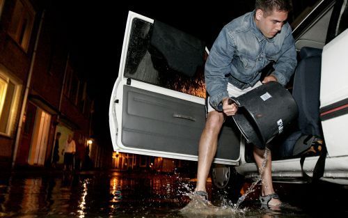 GORINCHEM - Een inwoner van Gorinchem hoost met een emmer het water uit zijn auto. De hevige regenval van woensdagavond heeft voor ernstige problemen gezorgd in de Zuid-Hollandse gemeente. In sommige huizen stond dertig tot veertig centimeter water, kelde