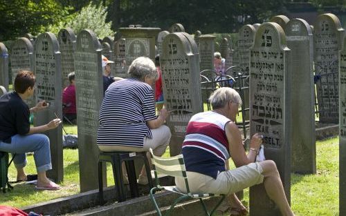 GRONINGEN â€“ Vrijwilligers herstellen joodse graven in Groningen. Door de Hebreeuwse tekens een zwart verfje te geven, komen ze weer tot hun recht. Foto Omke Oudeman