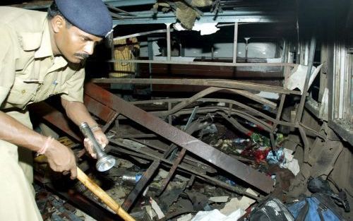 JAUNPUR â€“ Een Indiase politieman doet onderzoek tussen het puin van de passagierstrein waarin donderdag een bom ontplofte toen hij door de stad Jaunpur reed. De politie sluit een aanslag niet uit. Foto EPA