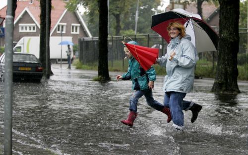 HILVERSUM â€“ Moeder en dochter in een ondergelopen straat in Hilversum. Stevige regen- en onweersbuien trokken vrijdag over het land en veroorzaakten veel overlast. Foto ANP