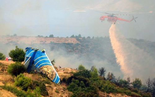 GRAMMATIKO â€“ De staart van de Boeing 737 van de Cypriotische maatschappij Helios Airways steekt boven het landschap uit terwijl rondom nog vuur nasmeult. Het toestel verongelukte zondag even ten noorden van de Griekse hoofdstad Athene. Daarbij kwamen al