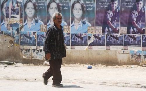 BAGDAD â€“ Posters promoten de Iraakse constitutie in Bagdad. Het Iraakse parlement stemde maandag in met een voorstel van Koerdische leiders om de commissie die de grondwet moet opstellen een week extra tijd te geven en de deadline te bepalen op 22 augus