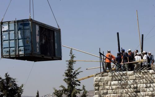 SANUR â€“ Joodse kolonisten in Sanur, op de Westelijke Jordaanoever, poogden dinsdag tot op het laatste moment ontruiming te voorkomen. Hier proberen ze een container met soldaten tegen te houden. Foto EPA