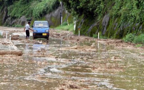 TOKIO - Een Japanse man loopt terug naar zijn auto die in de modder is vastgelopen een door de storm verzakte weg in Tarumizu, Zuid-Japan. De tyfoon Nabi trof dinsdag het zuidwesten van Japan. Foto EPA.